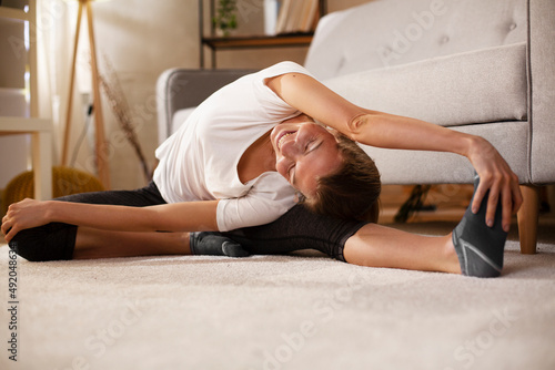 Young woman working out at home. Athletic woman in sportswear doing fitness stretching exercises..