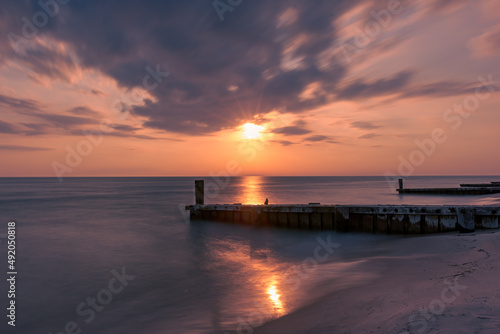 Obraz na plátně Sunset on the beach with the breakwater or jetty