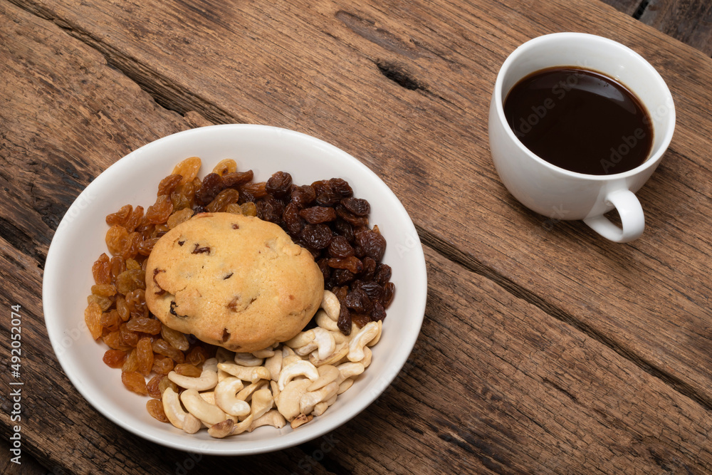 Black coffee cashew nuts raisin cookies in plate on wood table. Black coffee cashew nuts raisin cookies in plate on wood table.