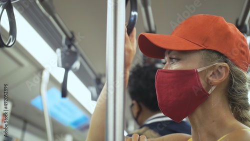 Woman travel caucasian ride at overground train airtrain with wearing protective medical red mask. Girl tourist at airtrain with respirator. Pandemic virus Coronavirus covid-19. People in mask. photo