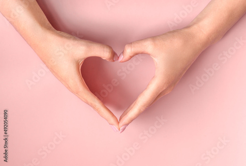 Nice female hands making heart on pink beige background. Beautiful young woman hands with copy space. Love  friendship  peace concept. Valentine day  Birthday  Mothers Day.