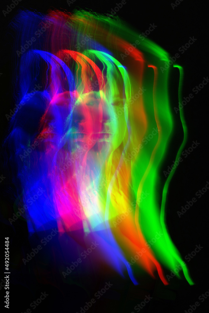 Abstract woman silhouette portrait in bright light trails of light painting in RGB split style of red, green and blue colors. Long exposure photo. Image contains noise and motion blur