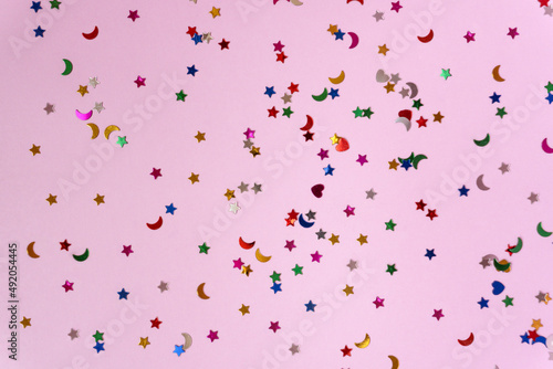 Festive pink background with many colorful stars and moons. Christmas, New Year or Birthday theme concept. An ideal backdrop for your banner or web design. Backplate for happy holidays presentation