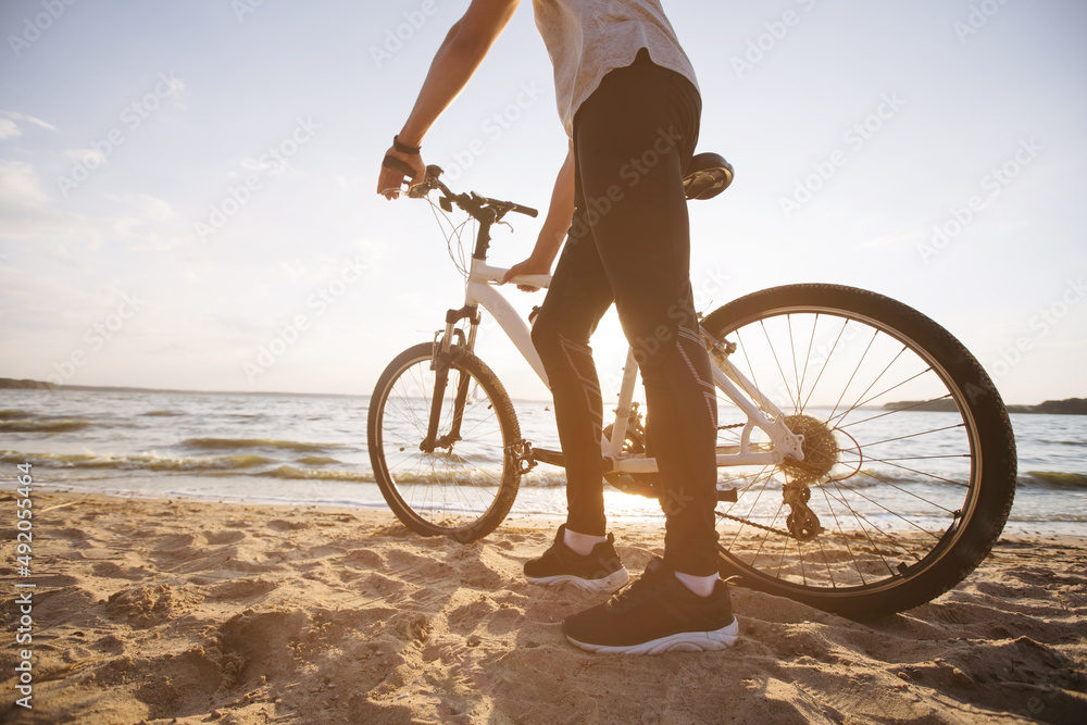 Fototapeta premium man with a bicycle standing on a sandy beach .