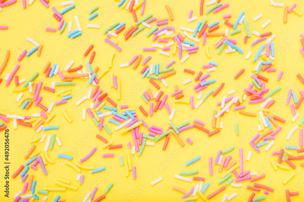 Colorful festive sugar sprinkles on yellow background. Flat lay style. Top view. Place for design. Easter background. Colorful festive sugar sprinkles on yellow background. Flat lay style. Top view. Place for design. Easter background.
