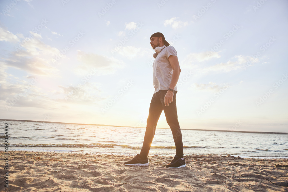 young man with headphones walking on the shore.