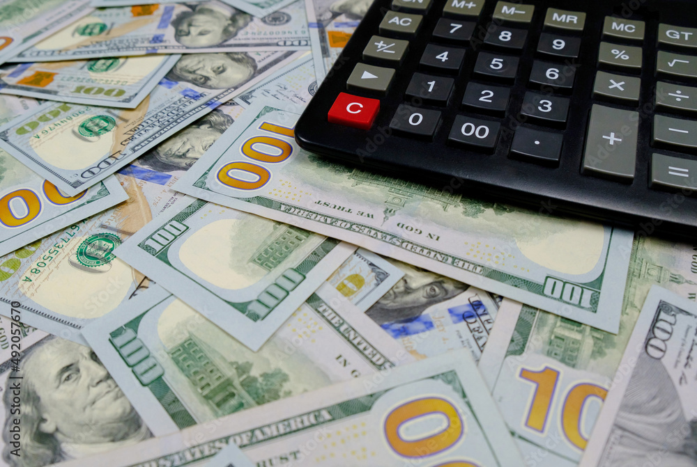 Calculator on the background of money. US dollars banknotes Calculator on the background of money. US dollars banknotes