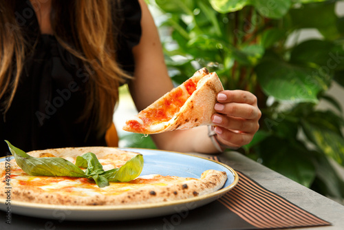 pizza tonda  farcita  servita su un piatto in un tavolo di una pizzeria mentre un sperona mangia una fetta photo