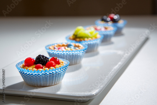 dolcetti con frutta in fila su piatto bianco  photo