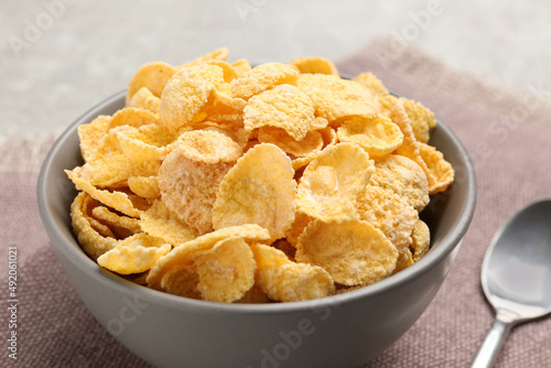 Bowl of sweet crispy corn flakes on kitchen towel, closeup. Breakfast cereal