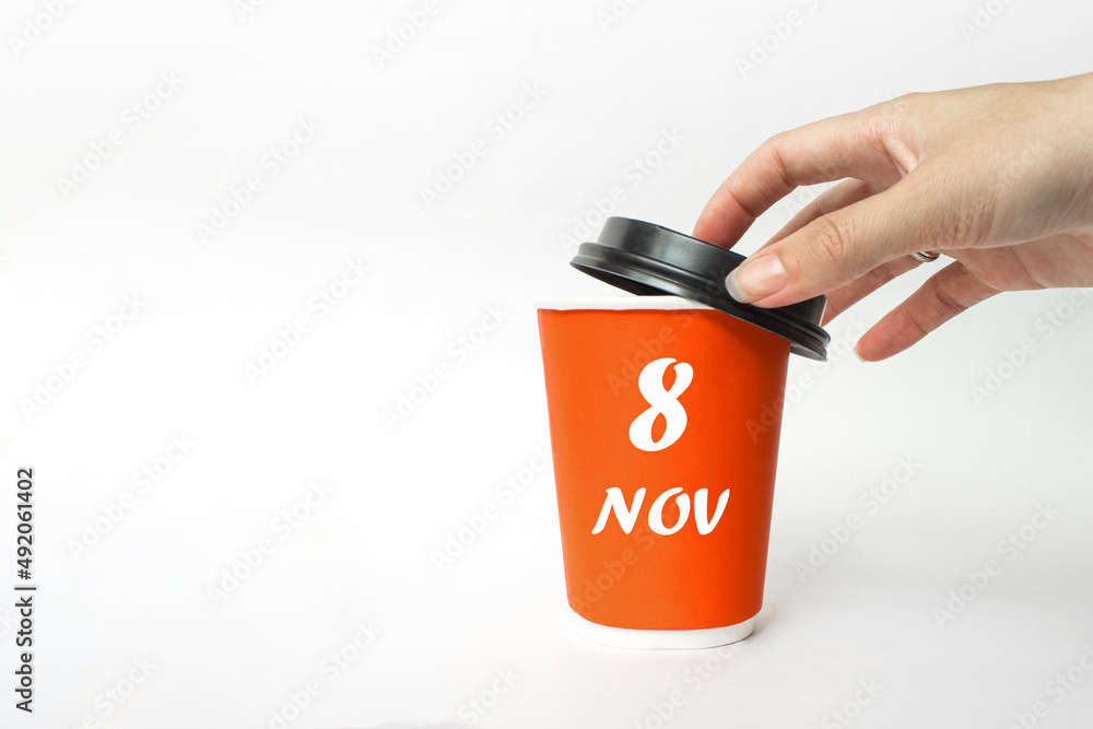 November 8th. Day 8 of month, Calendar date. A woman's hand open black plastic cap of red disposable cardboard coffee paper cup with Calendar Date. Autumn month, day of the year concept.