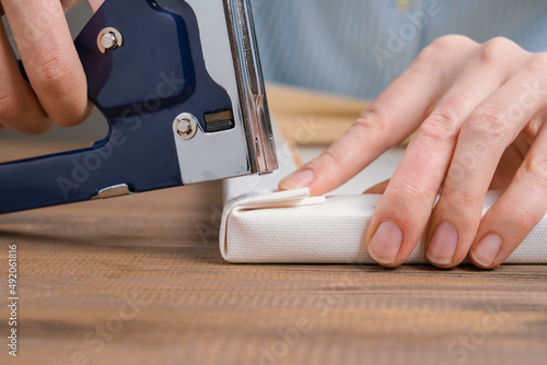 The artist stretches the canvas on a wooden stretcher, fixing the corner of the canvas with a stapler.