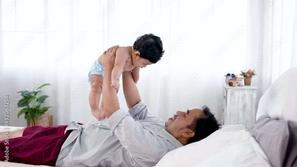 4k 50fps, cAsian single dad plays with newborn son in bedroom. He lifted his son up and pretended to be flying in the air with joy and fun. Concept Happy Family 4k 50fps, cAsian single dad plays with newborn son in bedroom. He lifted his son up and pretended to be flying in the air with joy and fun. Concept Happy Family