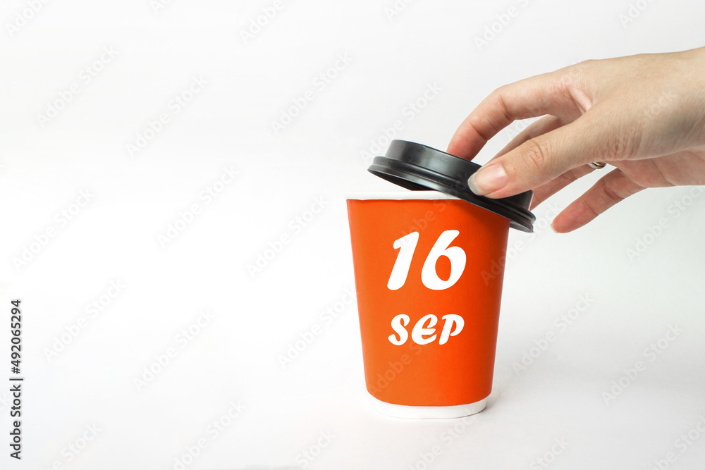 September 16th. Day 16 of month, Calendar date. A woman's hand open black plastic cap of red disposable cardboard coffee paper cup with Calendar Date. Autumn month, day of the year concept. September 16th. Day 16 of month, Calendar date. A woman's hand open black plastic cap of red disposable cardboard coffee paper cup with Calendar Date. Autumn month, day of the year concept.