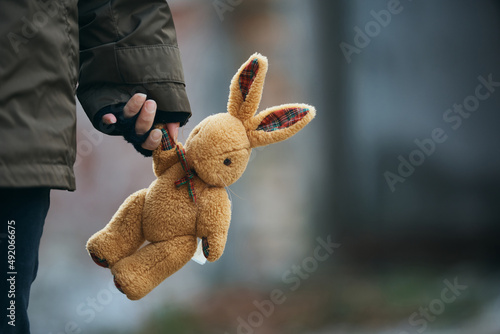 Quadro em tela Close-up of person carrying plush bunny while fleeing the war.