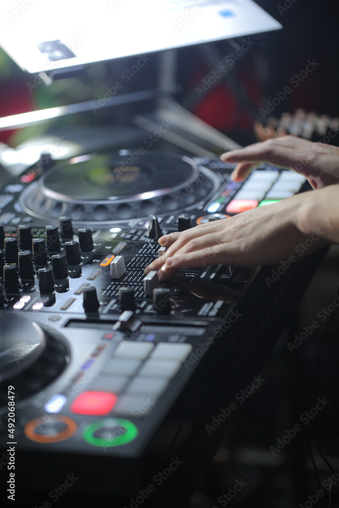 Close up of DJ hands controlling a music table in a night club Close up of DJ hands controlling a music table in a night club