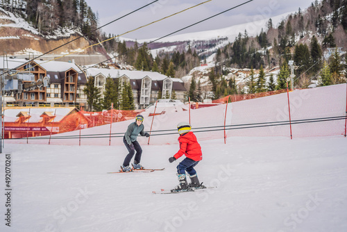 Фотография Boy learning to ski, training and listening to his ski instructor on the slope i