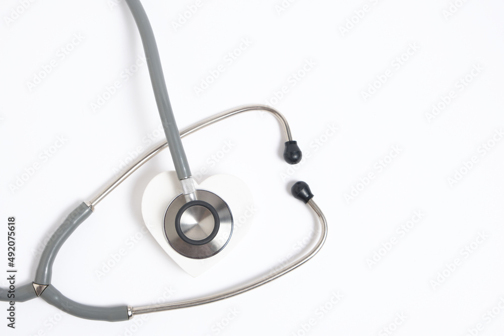White heart and stethoscope on white background.Heart disease, medical examination. White heart and stethoscope on white background.Heart disease, medical examination.