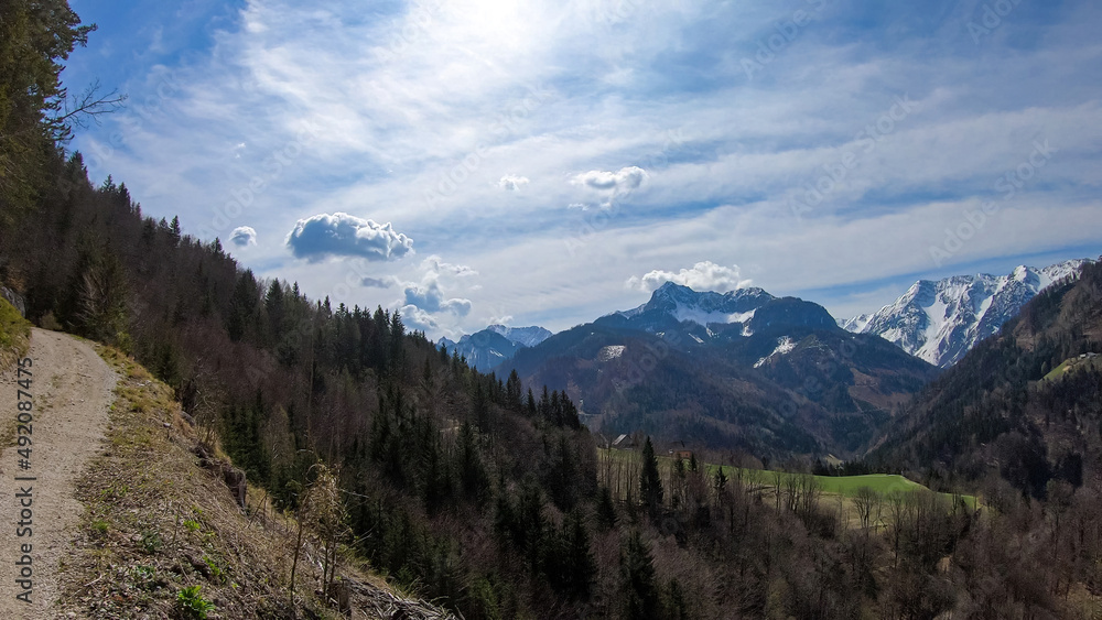Scenic view of a hiking trail leading to the snow capped mountain peaks of Karawanks near Sinacher Gupf in Carinthia, Austria. Mount Wertatscha and Hochstuhl (Stol) is visible in early spring.Rosental