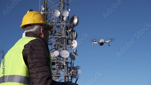 Old engineer operating a drone with remote control at the construction site. Civil engineer with safety helmet inspecting new construction site. Drone operator. Aerial survey.
