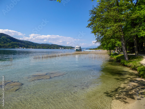 View on Woerthersee in Poertschach in Carinthia, Austria.A boat standing at the the lake shore. Turquoise colored water. Clear and sunny day. Calm and relaxed feeling. Alps, Lake Woerth photo