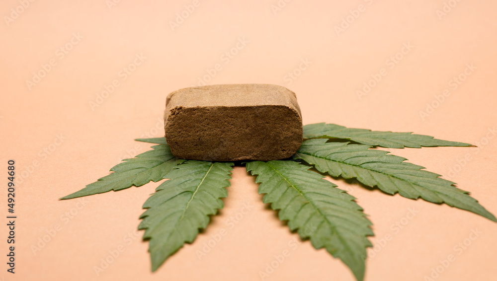 portion hashish tablet with marijuana leaf, bronw background - obrazy, fototapety, plakaty 