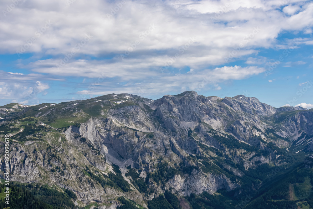 Fototapeta premium Panoramic view on the alpine mountain chains in Styria, Austria, Hochschwab region. Hills overgrown with small bushes, higher parts rocky and bare. Sunny summer day. Serenity. Hiking in Alps, Tragoess