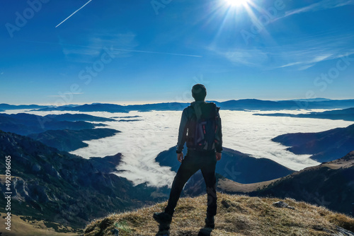 A man enjoying the panoramic view from mount Eisenerzer Reichenstein in Styria  Austria  Europe. The Ennstal valley is covered in clouds and fog.Hiking trail Wanderlust. Sunny day.Freedom concept