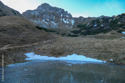 Frozen Krumpensee with a panoramic view on mount Eisenerzer Reichenstein in Styria, Austria, Europe. Austrian Alps. Ennstal Alps. The valley is in the shadows, sunrise. Hiking trail, Wanderlust. photo