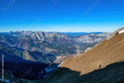 Panoramic view from mount Eisenerzer Reichenstein in Styria, Austria, Europe. Austrian Alps. View on the village Eisenerz in the Ennstal valley. Silhouette of hiker on alpine meadow. Wanderlust photo