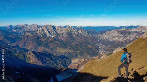 A man enjoying the panoramic view from mount Eisenerzer Reichenstein on the village Eisenerz in Styria, Austria, Europe. Austrian Alps. Lakes in the Ennstal valley. Hiking trail, Wanderlust. Sunny day