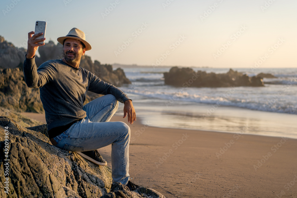 man taking selfies with smartphone and smiling on beach happy
