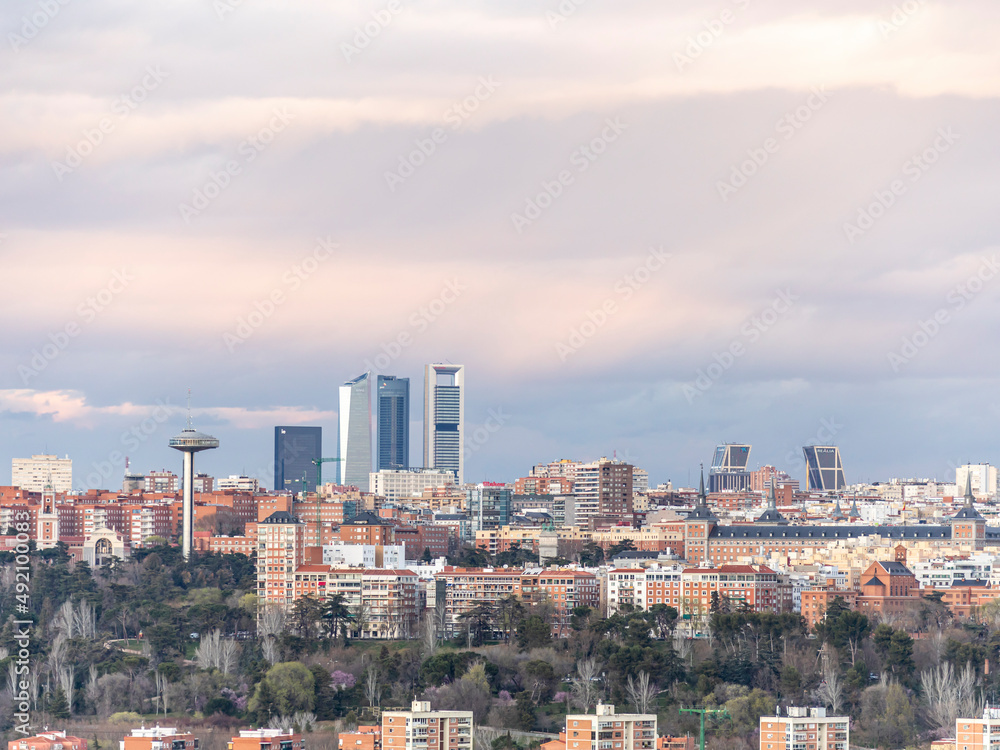 Views of the buildings of Madrid during the beginning of the sunset with some beautiful clouds and the Moncloa's Faro and the five tower in the background