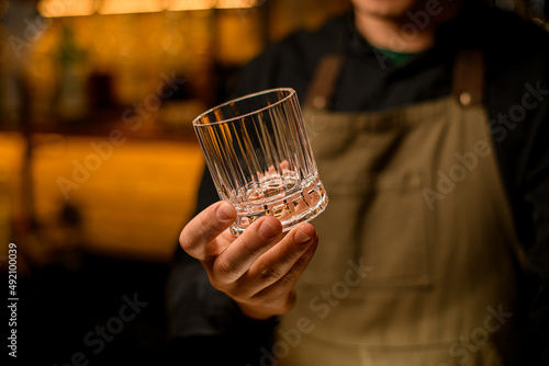 hand of bartender gently hold old-fashioned cocktail glass.