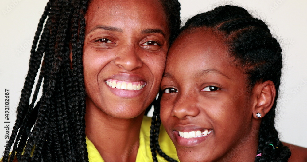 African mother and teen daughter smiling at camera posing together African mother and teen daughter smiling at camera posing together