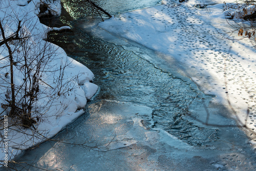 A washout in the ice, on a fast mountain river. A fast mountain river, broke through ice, snow and formed a washout.