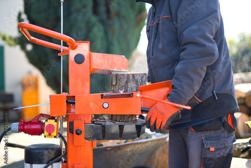 Close-up shot of a hydraulic wood splitter cutting fire wood on a sunny day photo