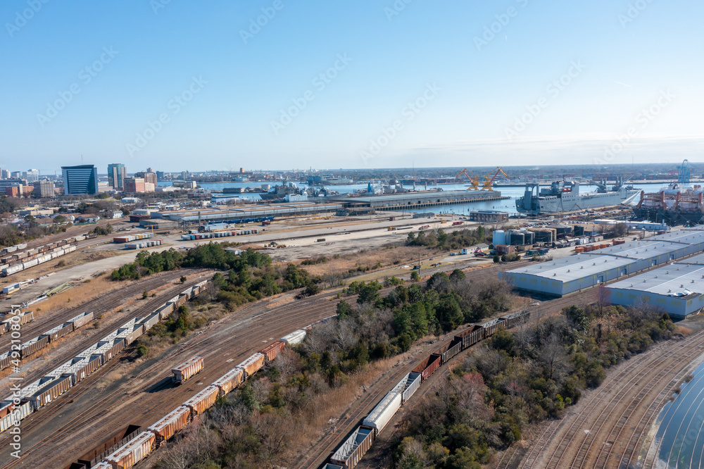Aerial view of a large industrial rail yard with freight train cars cargo ships and warehouses