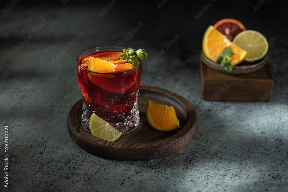 Refreshing sangria cocktail or punch with citrus orange lemon fruit in glasses . Sangria of red wine with ice. Traditional Spanish sangria . Drops from a squeezed orange