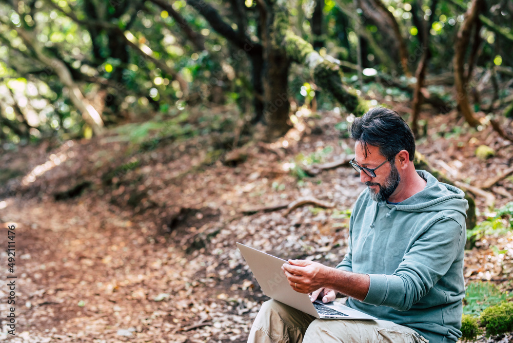 Modern people working outdoor with laptop computer and wireless internet data connection. Alternative online job and free travel lifestyle for remote worker people. Handsome male using computer Modern people working outdoor with laptop computer and wireless internet data connection. Alternative online job and free travel lifestyle for remote worker people. Handsome male using computer
