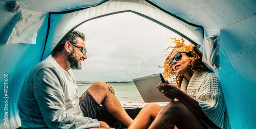 Canvas Print Caucasian adult couple smile and enjoy leisure inside a tent in free camping at the beach with sea view