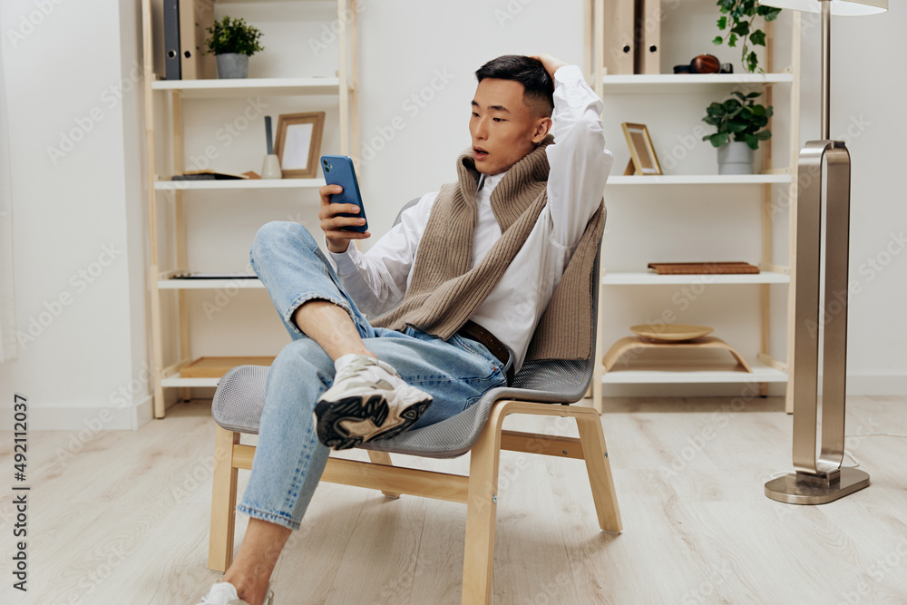 man sitting in a chair in a room with phone on his lap Lifestyle man sitting in a chair in a room with phone on his lap Lifestyle