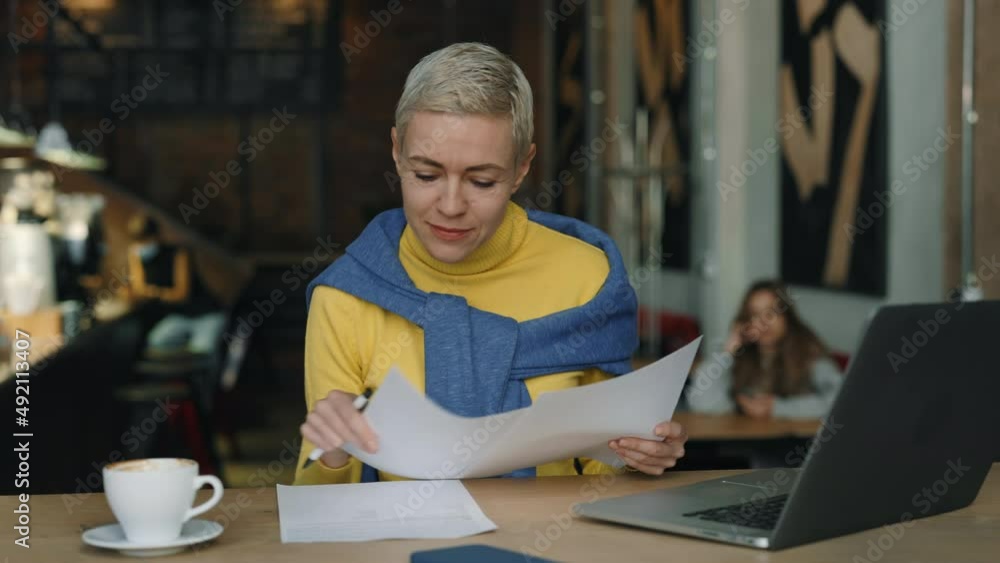 Woman typing on laptop and working with documents at cafe Woman typing on laptop and working with documents at cafe