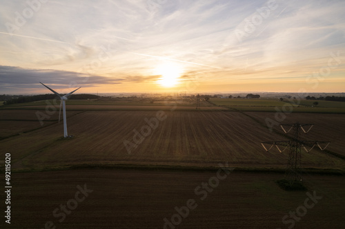 Wind turbine and pylon, side by side at sunrise
