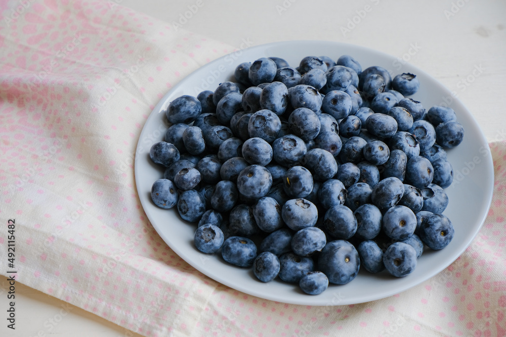 Fresh raw organic blueberries in a plate on a natural linen napkin on the table. Healthy nutrition. Minimalistic simple natural light flat lay template. Superfood. Organic eco health care. Vitamins. Fresh raw organic blueberries in a plate on a natural linen napkin on the table. Healthy nutrition. Minimalistic simple natural light flat lay template. Superfood. Organic eco health care. Vitamins.