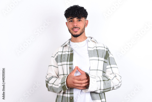 Business Concept - Portrait of young arab man with curly hair wearing overshirt over white background holding hands with confident face.