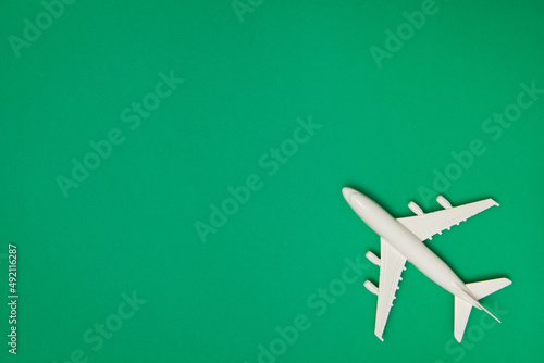 Airplane model. White plane on green background. Travel vacation concept. Summer background. Flat lay.
