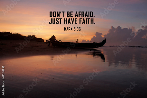 Bible verse inspirational quote - Don't be afraid, just have faith. Mark 5:36 On colorful sunrise background on the beach, with silhouette of fishing boat and the morning light. Christianity. photo