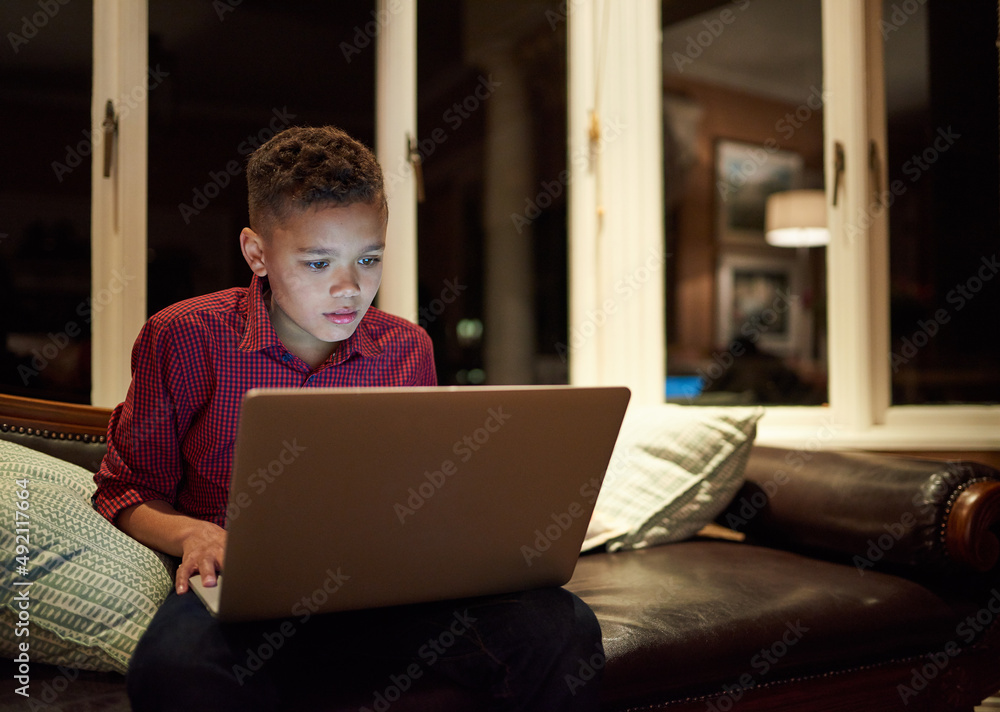 Too much tech too late. Shot of a young boy using a laptop past his bedtime at home. Too much tech too late. Shot of a young boy using a laptop past his bedtime at home.
