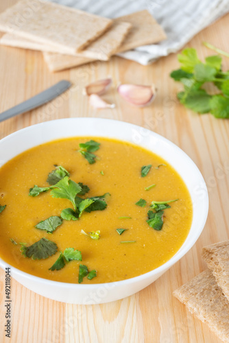Red lentil creamy soup served with parsley and crispbread. Homemade vegetable warm food.
